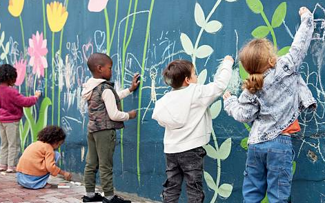 Children drawing flowers and plants on a colorful outdoor mural wall