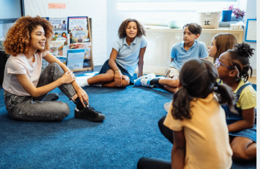 Mentor sitting in a circle on the classroom floor talking with a group of students