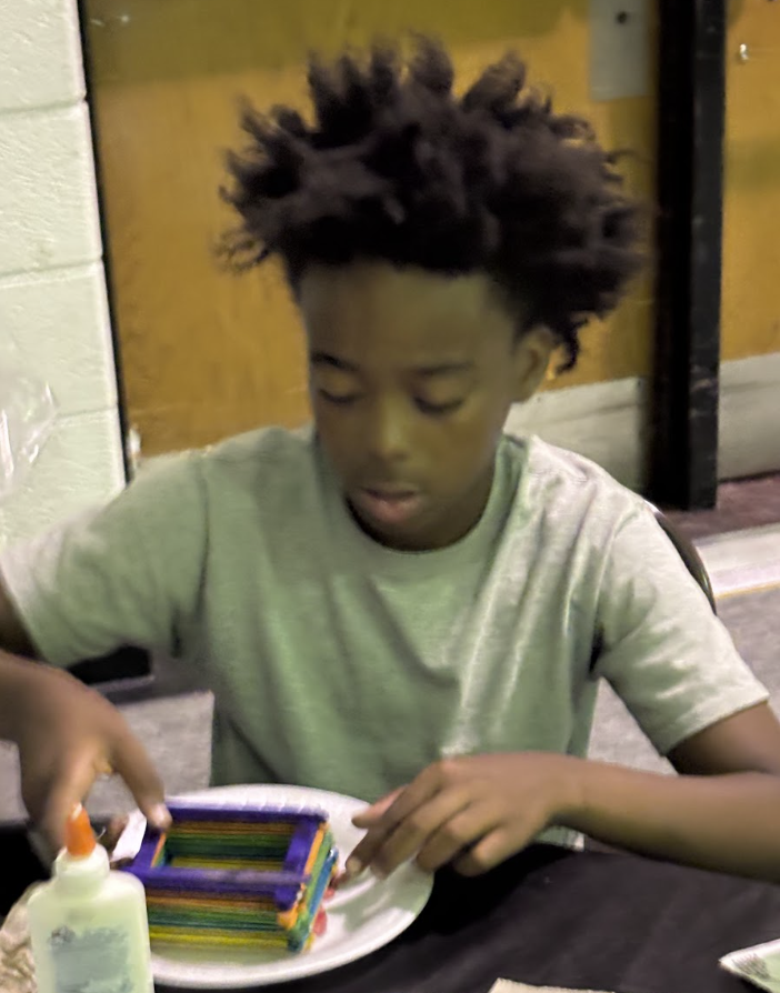Camp Ignite student focused on a craft project with popsicle sticks