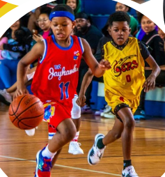 Two young basketball players in red and yellow jerseys competing for the ball